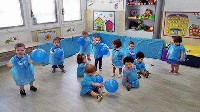 Un grupo de niños está jugando con globos azules en una habitación.