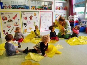 Un grupo de niños está sentado en el suelo con mantas amarillas.