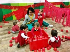 Un grupo de niños está jugando con pelotas rojas en una habitación.