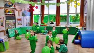 Un grupo de niños está jugando con globos verdes en una habitación.