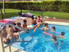 Un grupo de niños está sentado en el borde de una piscina.
