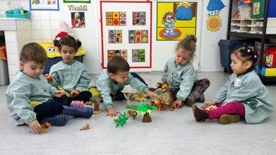 Un grupo de niños está sentado en el suelo jugando con juguetes.