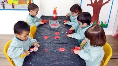 Un grupo de niños están sentados alrededor de una mesa jugando con juguetes.