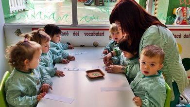 Un grupo de niños está sentado en una mesa con un profesor.