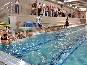 Un grupo de personas están de pie alrededor de una piscina.
