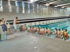 Un grupo de niños está sentado en el borde de una piscina.