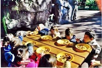 Un grupo de niños está sentado en una mesa con cuencos de comida.