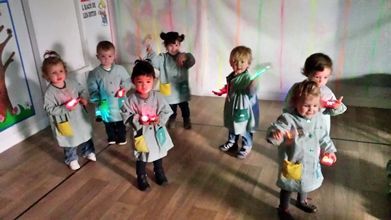 Un grupo de niños está de pie en una habitación sosteniendo luces en sus manos.