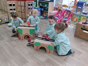 Un grupo de niños está jugando con juguetes de cartón en un aula.