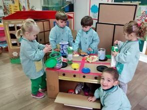Un grupo de niños está jugando con un juego de cocina de cartón.
