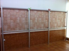 Una habitación con una pared de azulejos y una barandilla de metal.