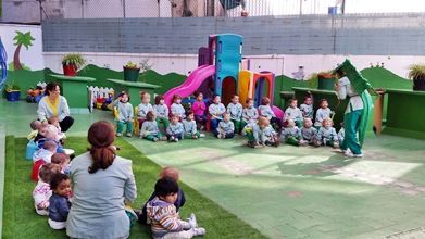 Un grupo de niños está sentado en el césped en un círculo.