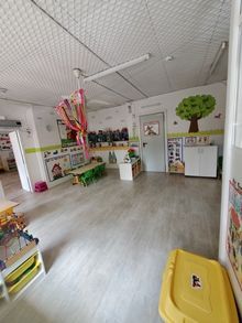 Una habitación grande llena de juguetes y un bote de basura amarillo.