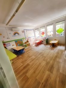 Una sala grande con pisos de madera, mesas y sillas.