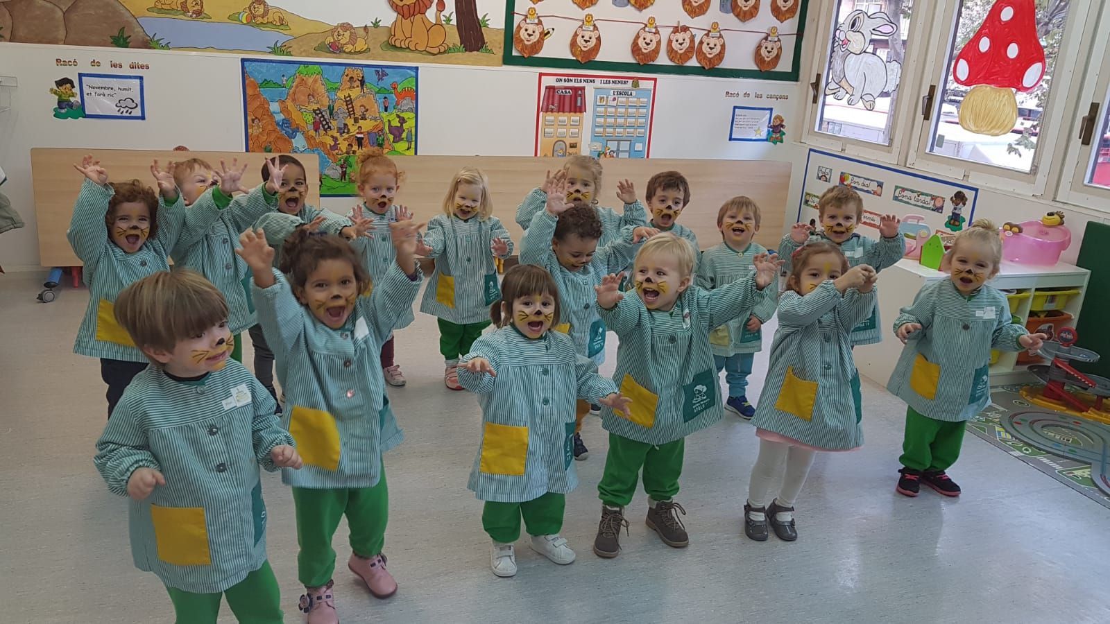 Un grupo de niños está de pie en una habitación con los brazos en el aire.