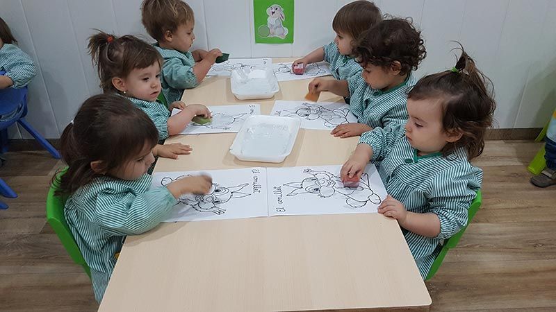Un grupo de niños pequeños están sentados en una mesa en un aula.