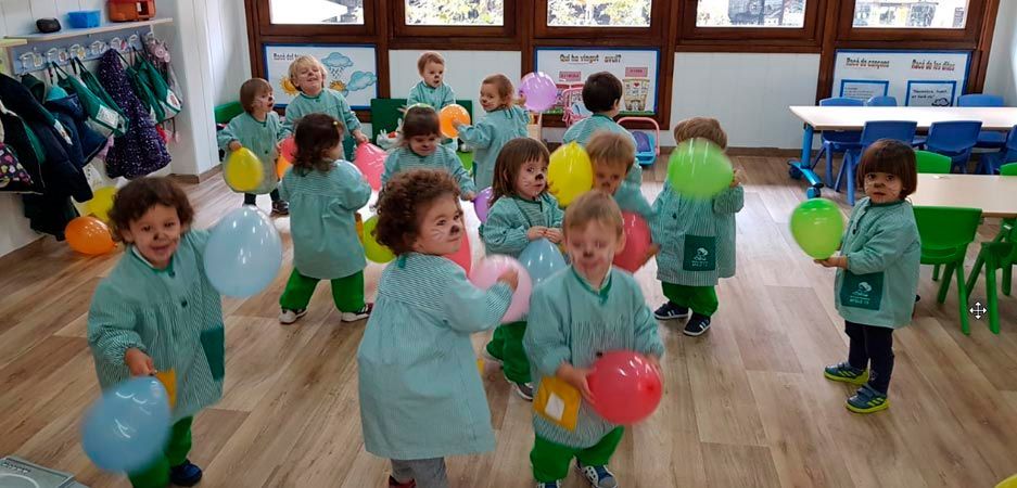 Un grupo de niños sostiene globos en un aula.