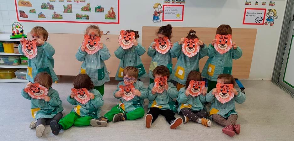Un grupo de niños con máscaras en un aula.