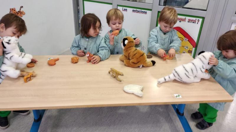 Un grupo de niños está jugando con animales de peluche en una mesa.