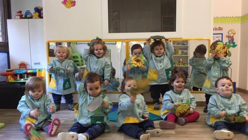 Un grupo de niños está sentado en el suelo tocando instrumentos.