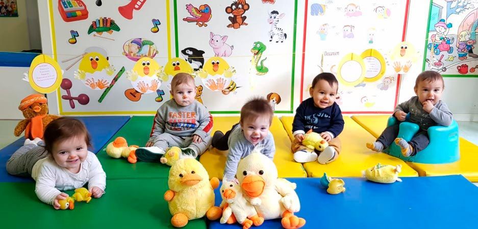Un grupo de bebés están acostados en el suelo con patitos de peluche.