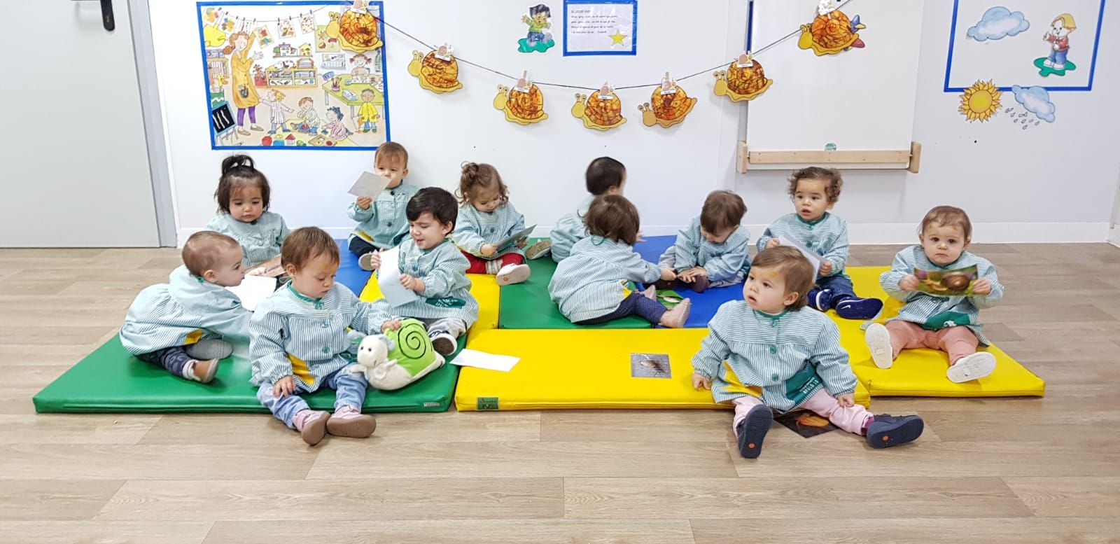 Un grupo de bebés está sentado sobre una estera en una habitación.