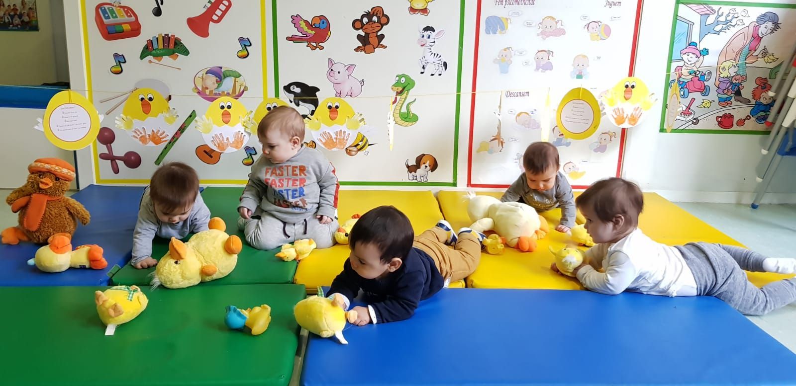Un grupo de bebés están acostados en el suelo jugando con animales de peluche.