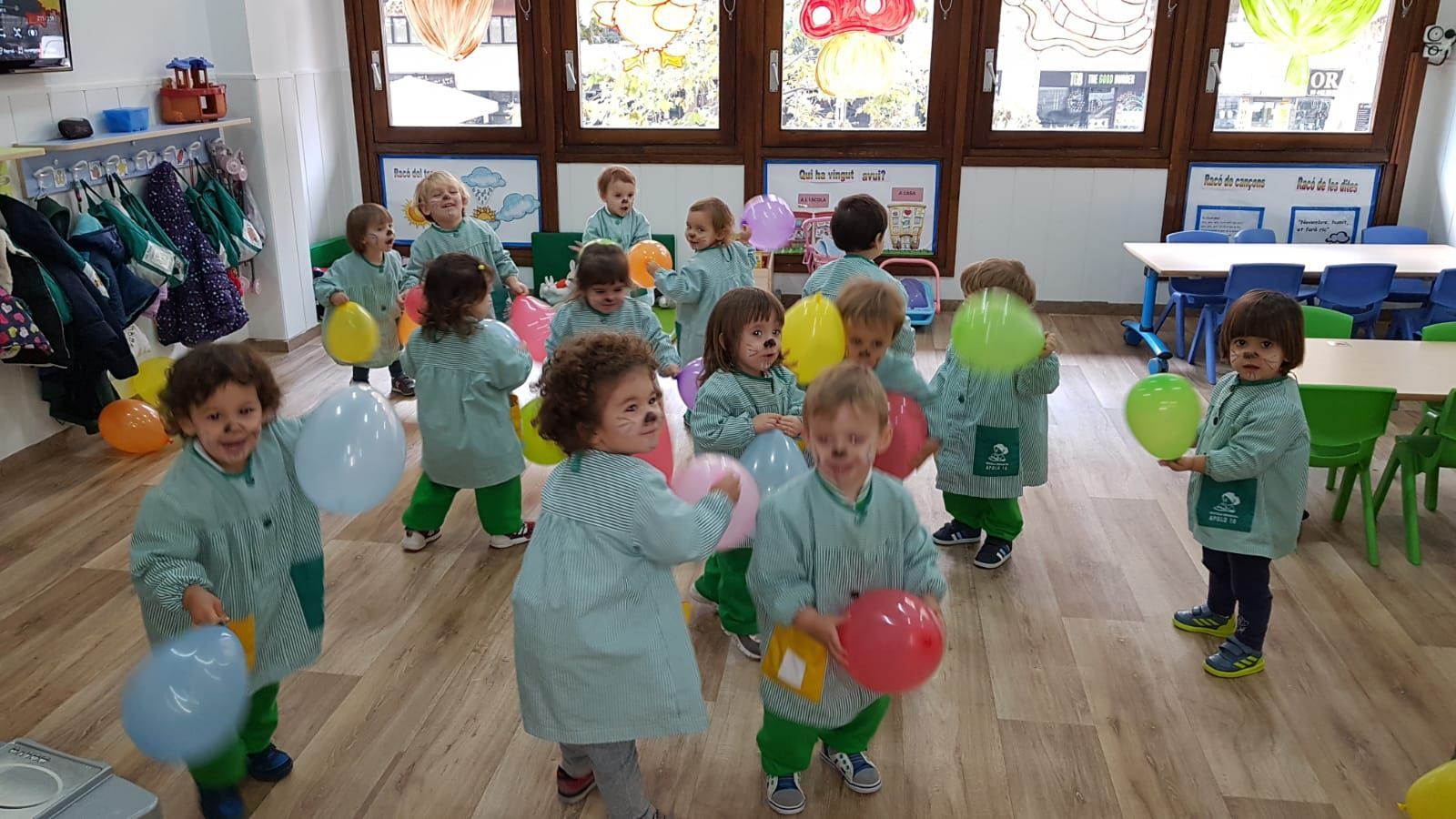 Un grupo de niños sostiene globos en un aula.