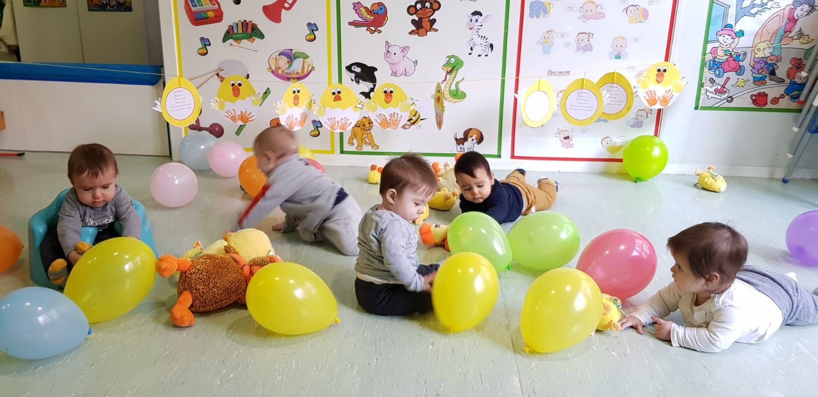 Un grupo de bebés está jugando con globos en el suelo.