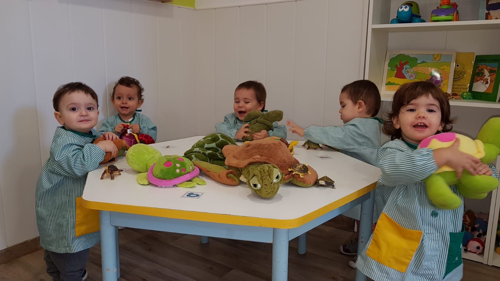 Un grupo de niños está jugando con animales de peluche en una mesa.