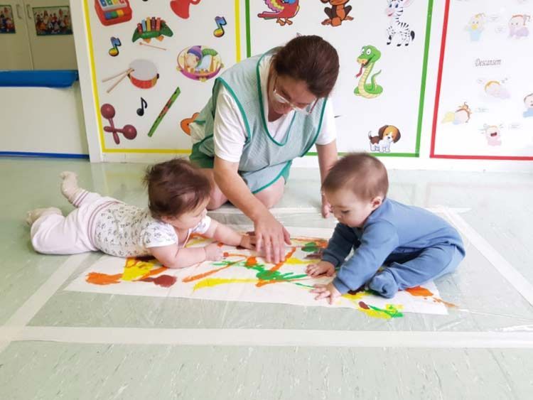 Una mujer está jugando con dos bebés en el suelo.