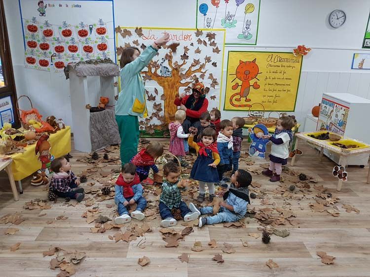 Un grupo de niños está jugando con hojas en un aula.
