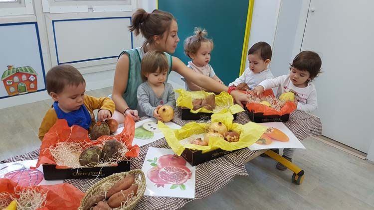 Un grupo de niños están sentados alrededor de una mesa con cajas de fruta.