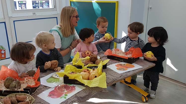 Un grupo de niños están sentados alrededor de una mesa comiendo fruta.