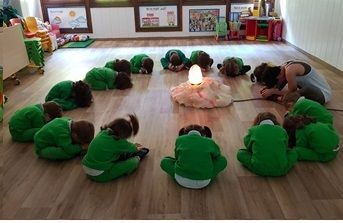 Un grupo de niños está arrodillado en círculo alrededor de una vela.