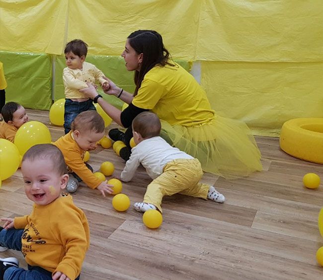 Un grupo de niños está jugando con pelotas amarillas en el suelo.