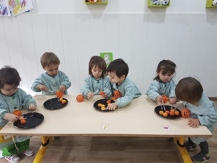Un grupo de niños está sentado en una mesa cortando zanahorias.