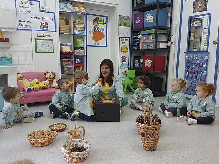 Un grupo de niños está sentado en el suelo en un aula con un profesor.