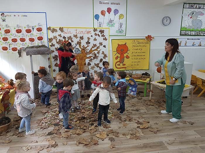Un grupo de niños está jugando con hojas en un aula.