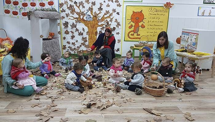 Un grupo de niños está sentado en el suelo jugando con hojas.