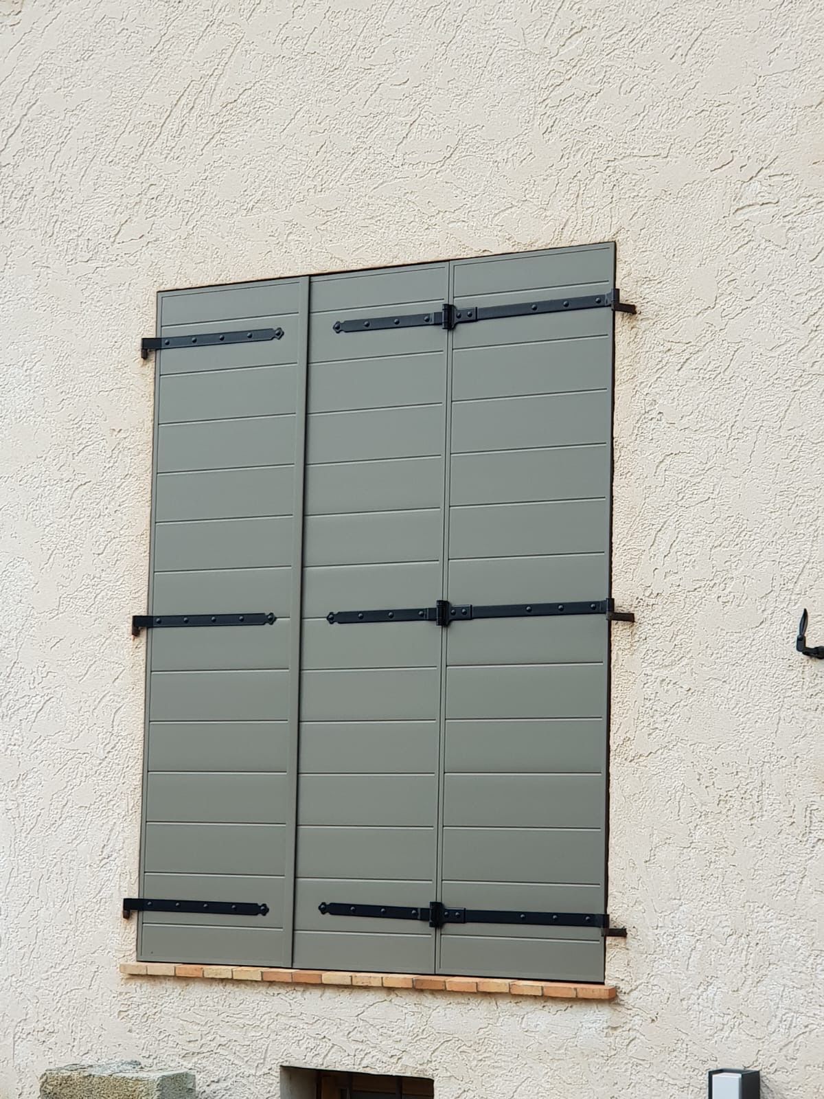 Fenêtre à volets gris sur un mur en stuc blanc