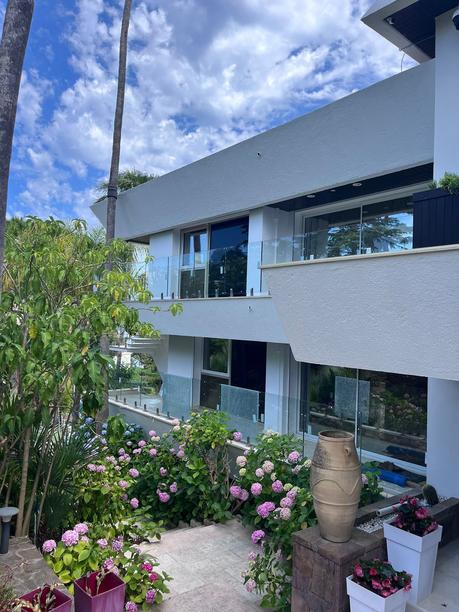 Maison moderne de deux étages avec façade en bois et en verre, terrasse et jardin paysager