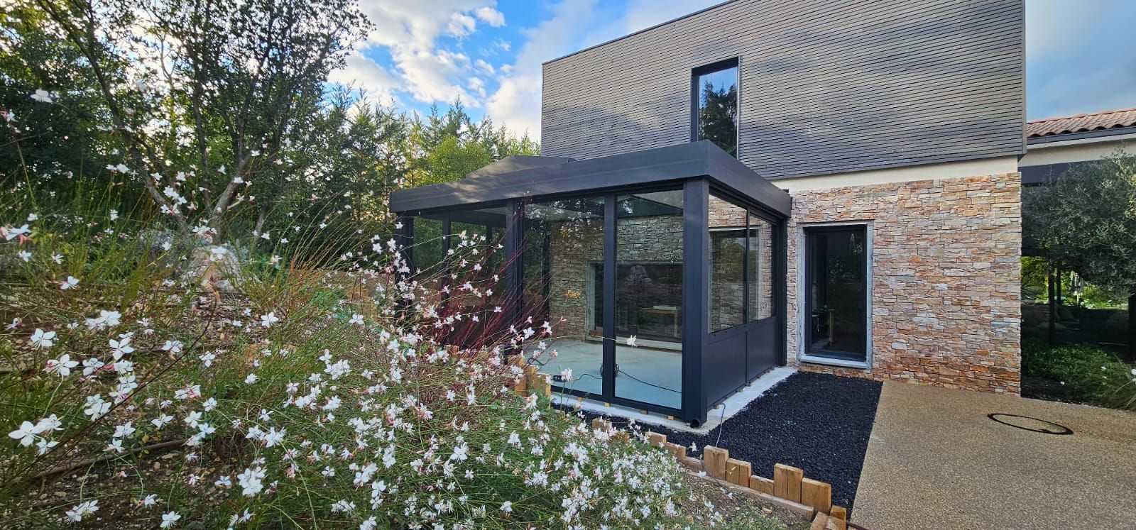 Maison moderne de deux étages avec façade en bois et en verre, terrasse et jardin paysager