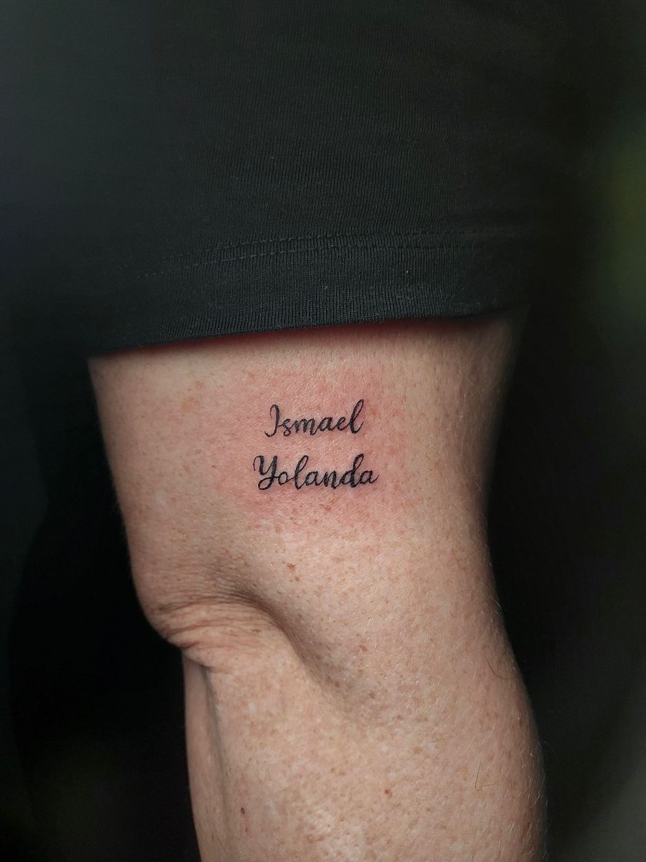 Un pequeño tatuaje de tinta negra en la piel con los nombres 