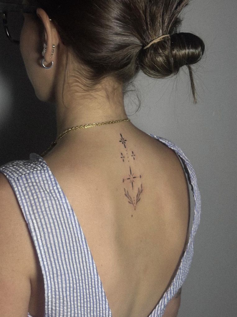 Primer plano de la parte superior de la espalda de una persona, donde se aprecia un delicado tatuaje vertical