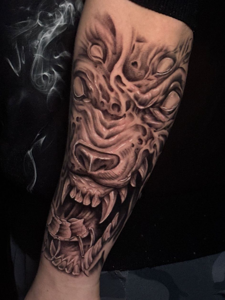 Tatuaje en blanco y negro en un antebrazo que representa una criatura surrealista con múltiples ojos