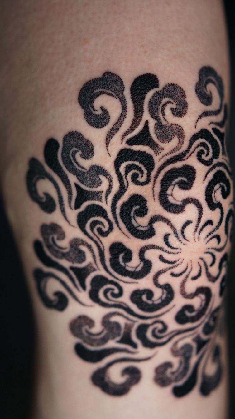 Un tatuaje de estilo blackwork sobre la piel que presenta un patrón radial de formas orgánicas ondulantes