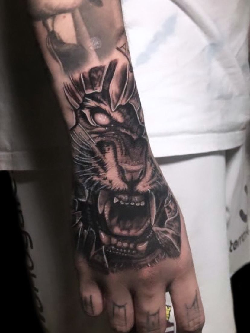 Un tatuaje detallado en blanco y negro de un tigre gruñendo con armadura de estilo samurái 