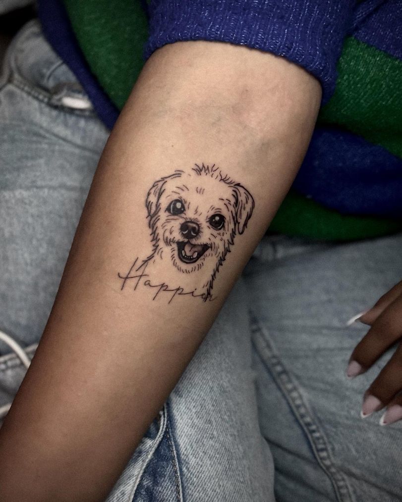 Un tatuaje en un brazo que representa un perro sonriente, dibujado al estilo de un boceto