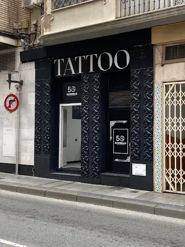 Fachada de un estudio de tatuajes con pilares negros de diseño geométrico, la palabra